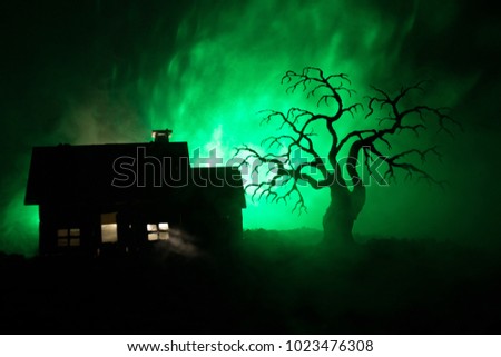 Old house with a Ghost at night with spooky tree or Abandoned Haunted Horror House in toned foggy sky with light. Old mystic building in dead tree forest. Horror Halloween concept.
