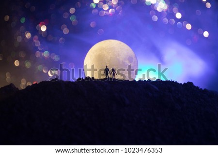 Amazing love scene. Silhouettes of young romantic couple standing under the moon light. Valentine`s day concept