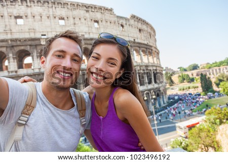 Travel selfie couple taking photo with phone at colosseum famous landmark in Rome city. Europe Italy summer vacation young people smiling. Backpacking road trip.