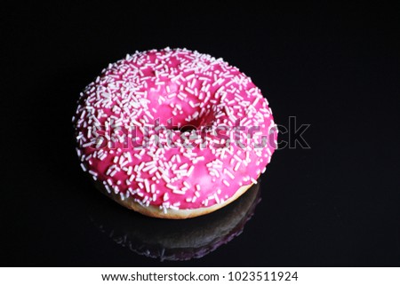 Donut on black reflective studio background. Isolated black shiny mirror mirrored background for every concept. Pink donut.