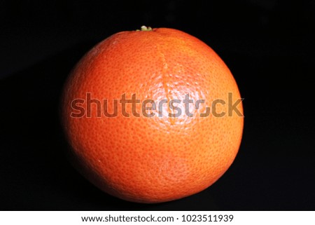 Whole grapefruit on black reflective studio background. Isolated black shiny mirror mirrored background for every concept.