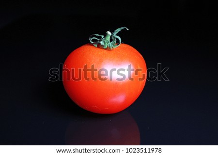 Tomato on black reflective studio background. Isolated black shiny mirror mirrored background for every concept..