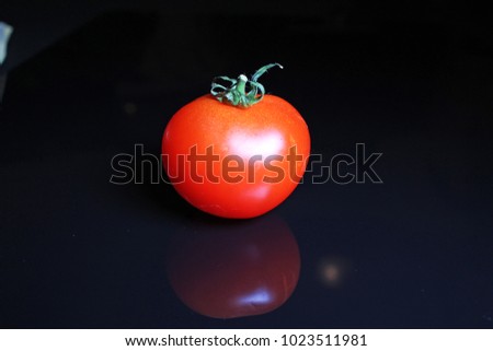 Tomato on black reflective studio background. Isolated black shiny mirror mirrored background for every concept.