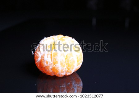 Peeled mandarin on black reflective studio background. Isolated black shiny mirror mirrored background for every concept..