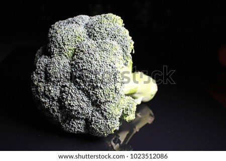Green whole broccoli on black reflective studio background. Isolated black shiny mirror mirrored background for every concept..
