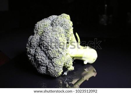 Green whole broccoli on black reflective studio background. Isolated black shiny mirror mirrored background for every concept..