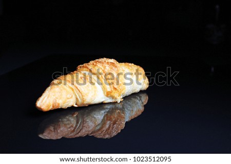 Croissant on black reflective studio background. Isolated black shiny mirror mirrored background for every concept..