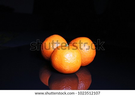 Mandarins on black reflective studio background. Isolated black shiny mirror mirrored background for every concept..