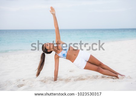 Side plank yoga fitness girl training balance strengthening abs muscles and wrist, toning body with core workout training outside on beach. Asian woman doing bodyweight exercise.