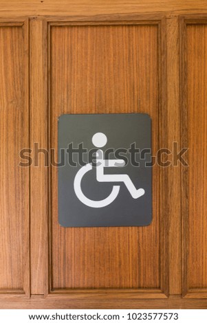 An accessible sign for disability people in front of the restroom door.
