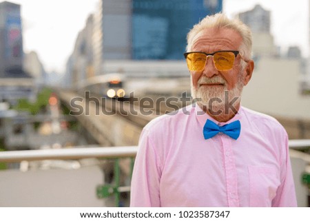 Portrait of handsome senior tourist man wearing stylish clothes while exploring the city of Bangkok, Thailand