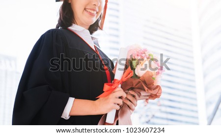 Happy Beautiful young woman graduate hand holding diploma and Flower bouquet at graduate ceremony. Royalty-Free Stock Photo #1023607234