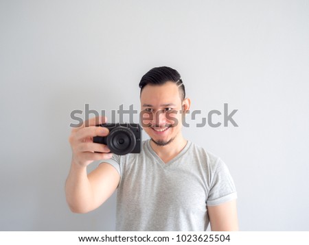 Asian man is holding a mirrorless camera and try to take a photo.