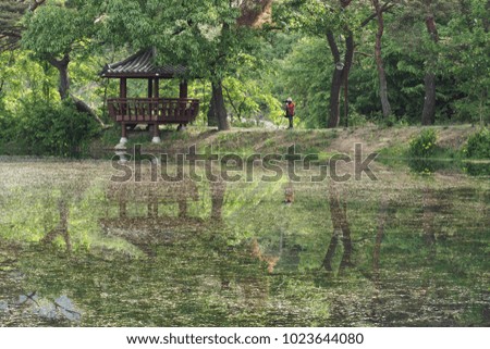 Reflection of gazebo and photographer at the spring lake