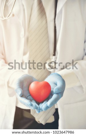 Doctor with blue rubber gloves holding a red heart.Concepts about health care.