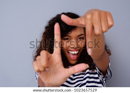 Close up portrait of happy young black woman smiling and making picture frame with fingers