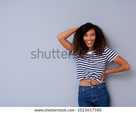 Portrait of cheerful young black woman laughing against gray background