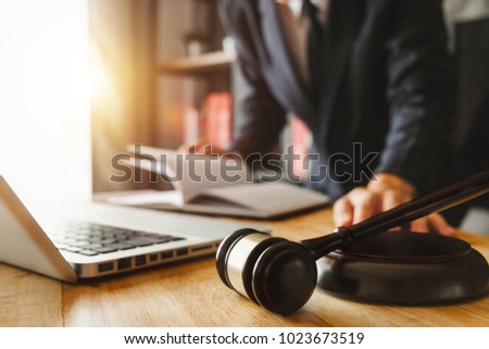 justice and law concept.Male judge in a courtroom  the gavel,working with digital tablet computer on wood table in morning light 
