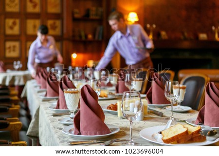 Waiters prepare a table for breakfast. Background. The foreground of napkins, dishes, toast, glasses. Calm atmosphere Royalty-Free Stock Photo #1023696004