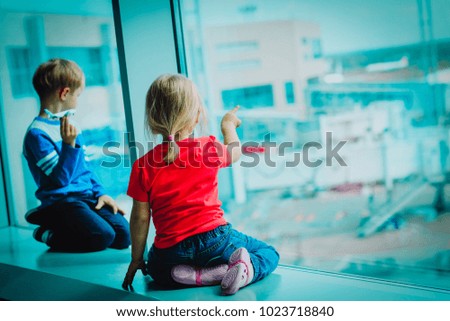 little boy and girl waiting plane in airport