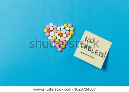 Medication white, colorful round tablets in form of heart isolated on blue background. Pills shape, paper sticker sheet, no tablets. Concept of health, treatment, choice healthy lifestyle. Copy space
