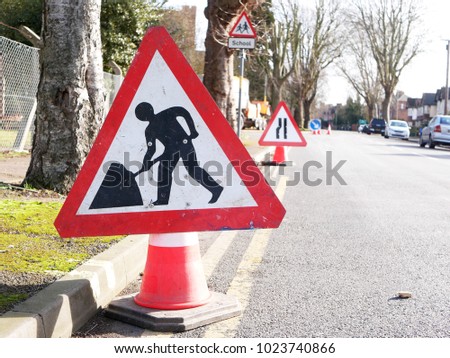 Roadworks sign and road narrows sign and school sign around tree felling operation on suburban street in a British city