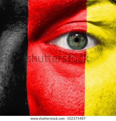 Flag painted on face with green eye to show Belgium support in sport matches