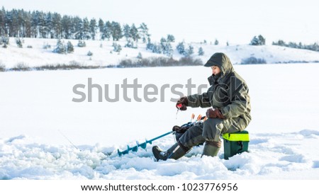 A young man is fishing from a hole on ice. Winter fishing. Royalty-Free Stock Photo #1023776956