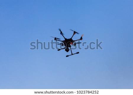 Professional drone hovering against clear blue sky