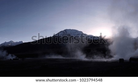 A panorama of the El Tatio geyser field with steam rising in the morning. 