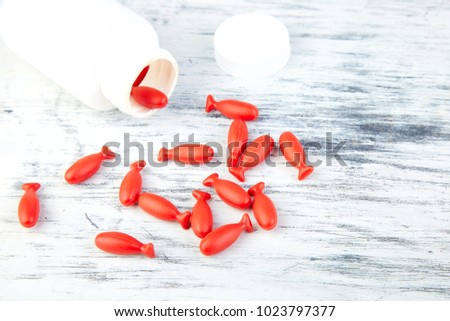 Omega 3 in fish shaped. Red capsules of Fish oil in bottle on white background. Copy space.