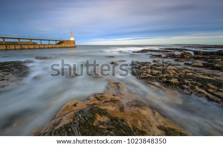 Long exposure of the sea and rocks surrounding Amble pier, Northumberland, England Royalty-Free Stock Photo #1023848350
