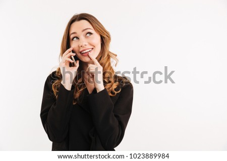 Fabulous businesswoman with long auburn hair in black outfit having mobile call and talking with pleasure isolated over white background