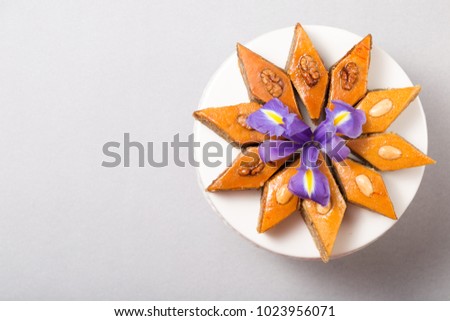 Plate of traditional national Azerbaijan baked pastry dessert pakhlava baklava with walnuts in white plate Novruz holiday spring celebration on light grey background copy space for text, greeting card