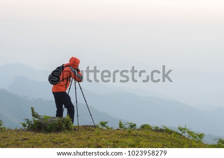 Photographer with tripod and camera taking picture of forest and mountain, natural background, sunset view