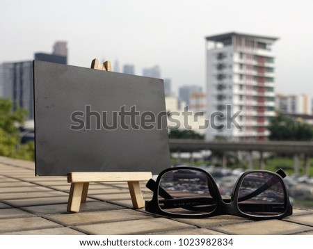 Conceptual prop - a black board with spectacle or eyeware on the floor with a blur background of a cityscape.