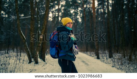 Side view of girl with backpack in winter forest