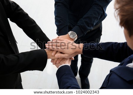 Men putting hands together indoors. Unity concept
