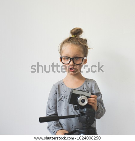 little girl with a camera on a white background. emotional child. the child portrays surprise