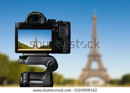 Camera on a tridop takes a picture of an Eiffel tower in Paris