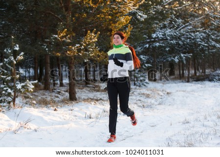 Photo of athlete brunette in sneakers on morning run against tree in winter