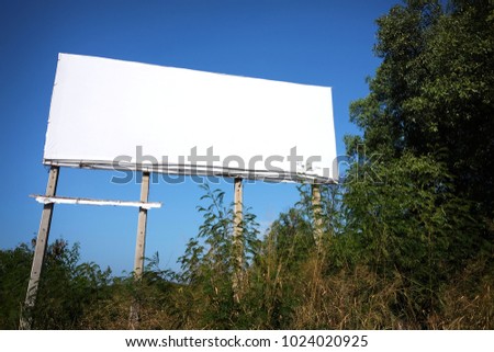 Blank white billboard on abandon land in daylight.