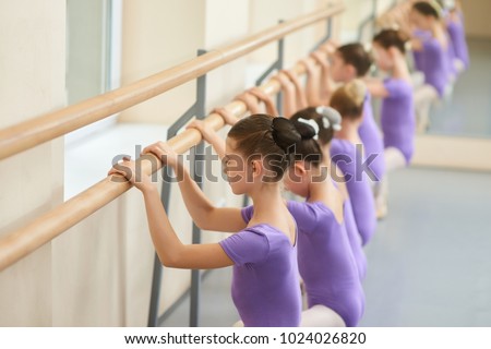 Ballerinas doing exercises at ballet barre. Lesson of classical ballet dance for children. Group of young ballet dancers.
