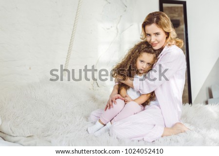 attractive mother hugging her upset little daughter on sheep skin blanket