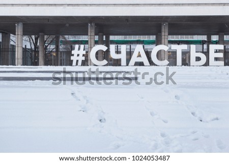 outdoor sign with text panel "Happy" in the snow in the city park