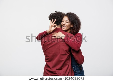 Portrait of a cheerful young african couple standing together and showing ok gesture isolated over white background