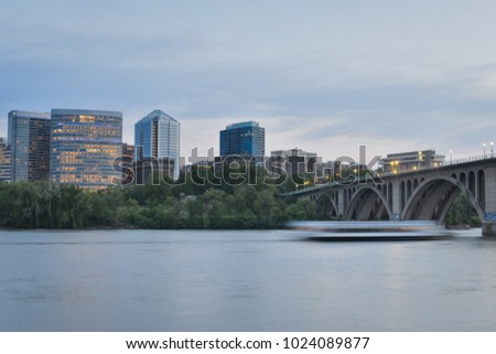 Washington DC - Key Bridge, Rosslyn skyscrapers and tourist boat in motion blur in Potomac River