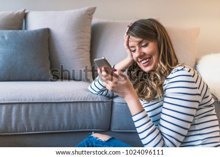 Young hipster girl using modern smartphone device while sitting at home and communicate with friends in social networks,female freelancer working from home, happiness and enjoyment lifestyle