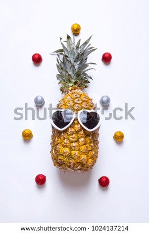 pineapple with sunglasses & colorful christmas baubles on white background.