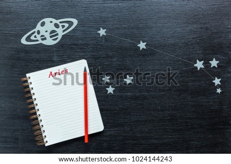 Zodiacal star, constellations Aries on a black background with a notepad and pencil.
